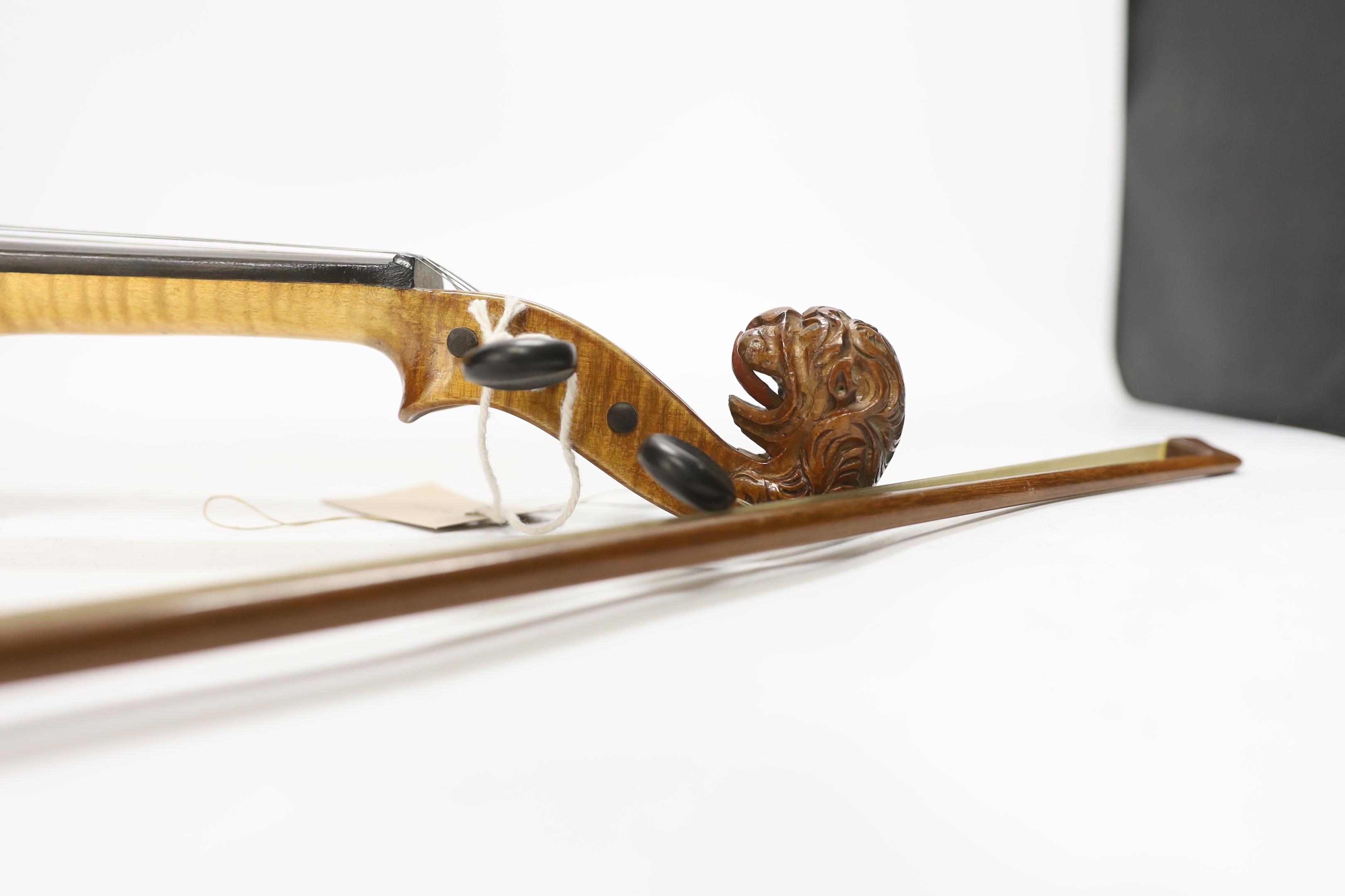 A 'travelling' violin and bow, the violin with grotesque head scroll carving, body 30.5cm